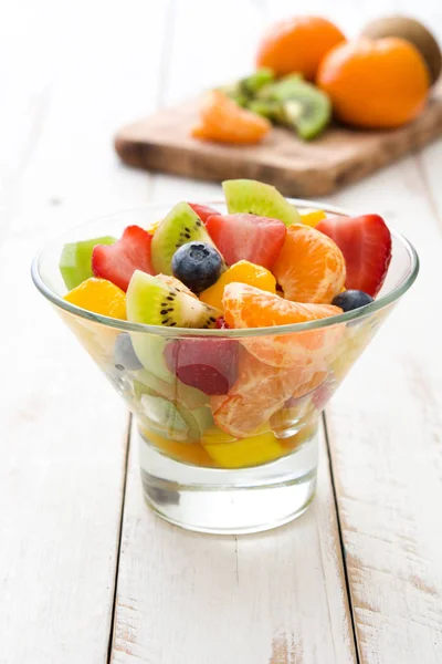 Salade de fruits dans un bol en cristal sur une table en bois blanc . — Photo