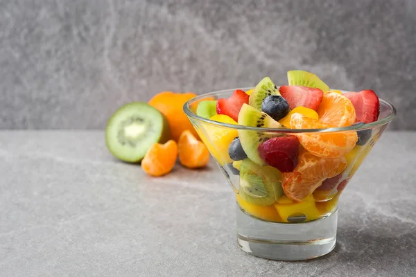 Insalata di frutta in ciotola di cristallo su pietra grigia — Foto Stock