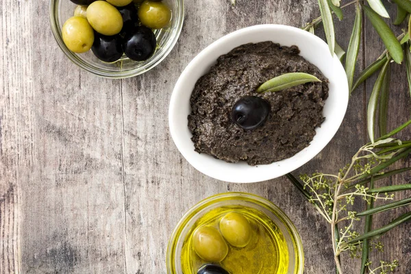 Czarnych oliwek tapenade z anchois, czosnku i oliwy z oliwek na podłoże drewniane — Zdjęcie stockowe