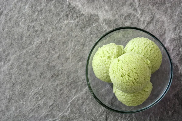 Green tea matcha ice cream scoops in crystal bowl on gray stone background — Stock Photo, Image