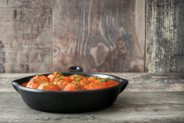 Ahşap masa üzerinde demir tavada domates soslu köfte