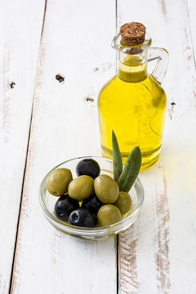Aceite de oliva virgen en una botella de cristal sobre una mesa de madera blanca — Foto de Stock