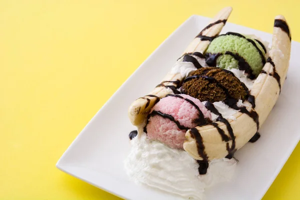 Bananen-Eis-Dessert mit Schokoladensirup auf gelbem Hintergrund — Stockfoto