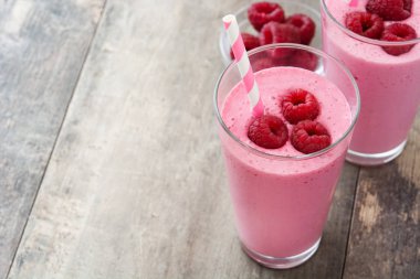 Ahşap masada cam içinde ahududu smoothie