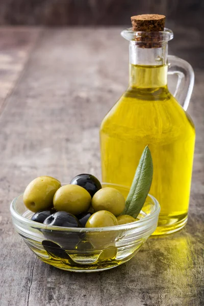 Aceite de oliva virgen en una botella de cristal sobre fondo de madera — Foto de Stock