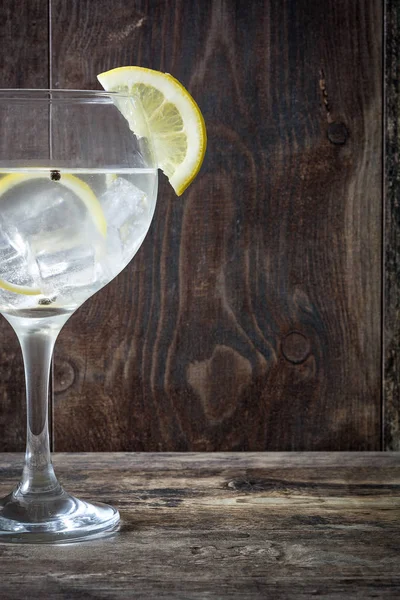 Glass of gin tonic with lemon on wooden background — Stock Photo, Image