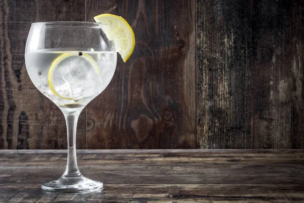 Glass of gin tonic with lemon on wooden background — Stock Photo, Image