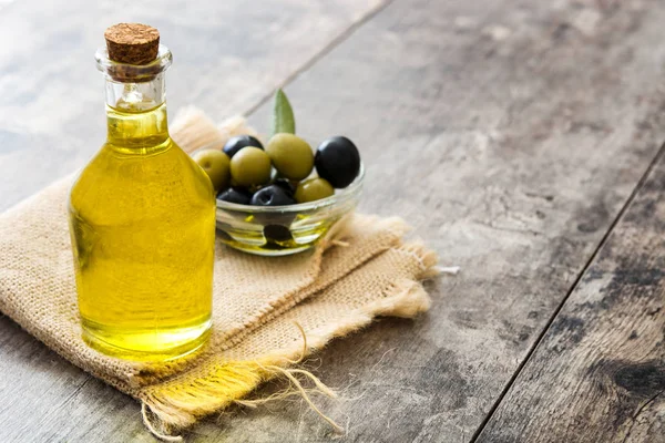 Aceite de oliva virgen en una botella de cristal sobre fondo de madera — Foto de Stock