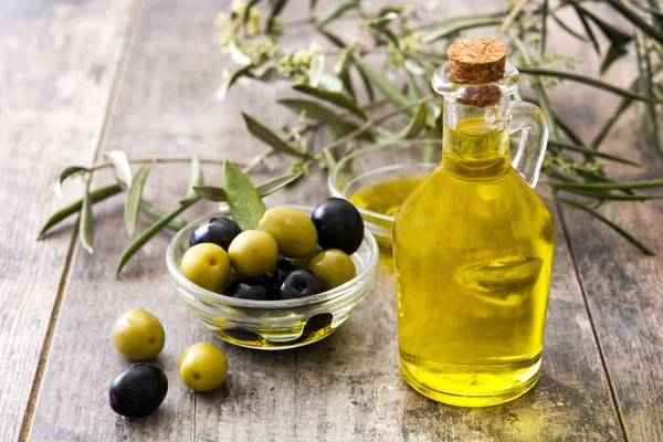 Aceite de oliva virgen en una botella de cristal sobre fondo de madera — Foto de Stock