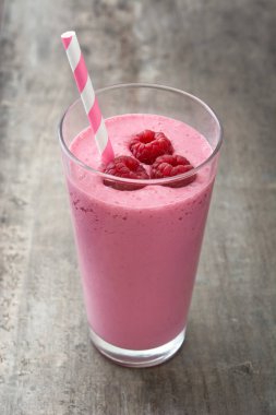 Ahşap masada cam içinde ahududu smoothie