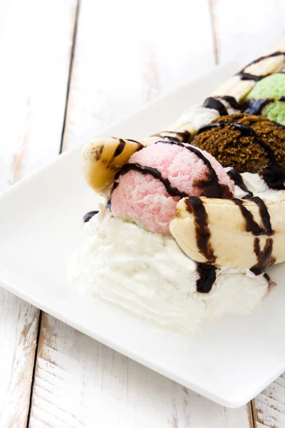 Banana split ice cream dessert with chocolate syrup on white wooden table — Stock Photo, Image