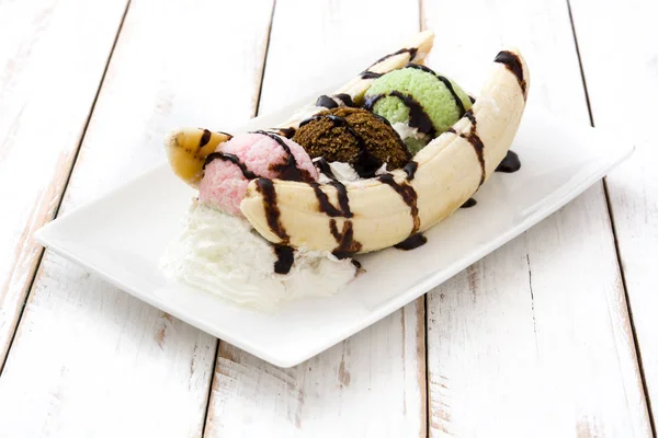 Banana split ice cream dessert with chocolate syrup on white wooden table — Stock Photo, Image