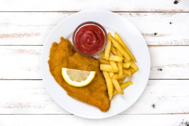 Beyaz ahşap zemin üzerinde patates kızartması ile Wiener schnitzel