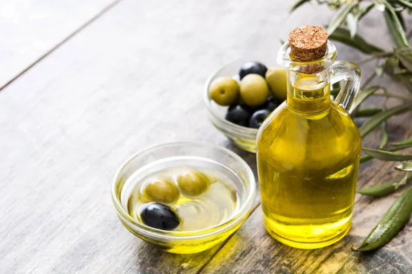 Oliwa z oliwek pierwszego tłoczenia w butelce kryształ na podłoże drewniane — Zdjęcie stockowe