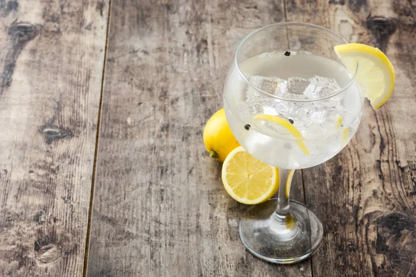 Vaso de gin tonic con limón sobre fondo de madera — Foto de Stock