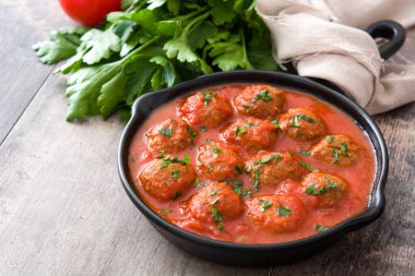 Ahşap masa üzerinde demir tavada domates soslu köfte