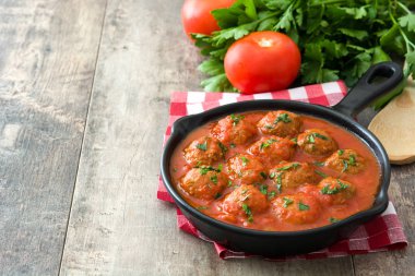 Ahşap masa üzerinde demir tavada domates soslu köfte