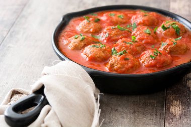 Ahşap masa üzerinde demir tavada domates soslu köfte