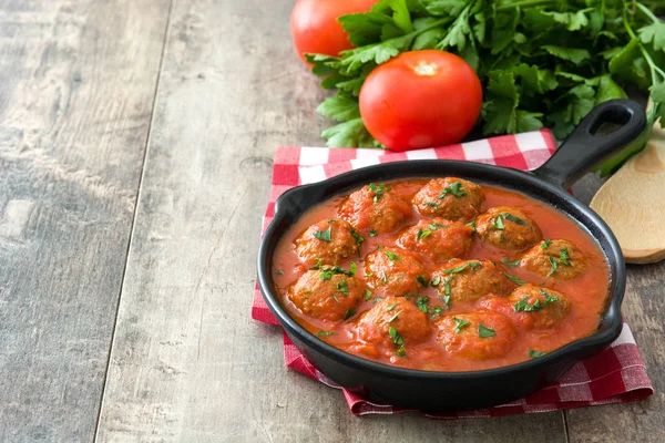 Albóndigas con salsa de tomate en sartén de hierro sobre mesa de madera — Foto de Stock