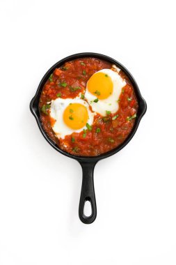 Mexican breakfast: Huevos rancheros in iron frying pan isolated on white background clipart
