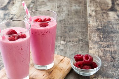 Ahşap masada cam içinde ahududu smoothie