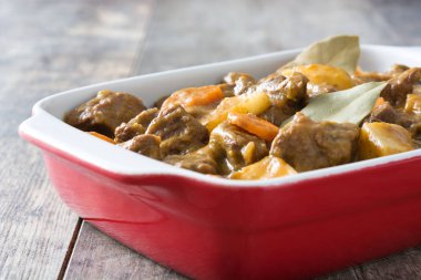 Patates, havuç ve ahşap masa üzerinde seramik tencerede baharatlar ile sığır eti Komposto