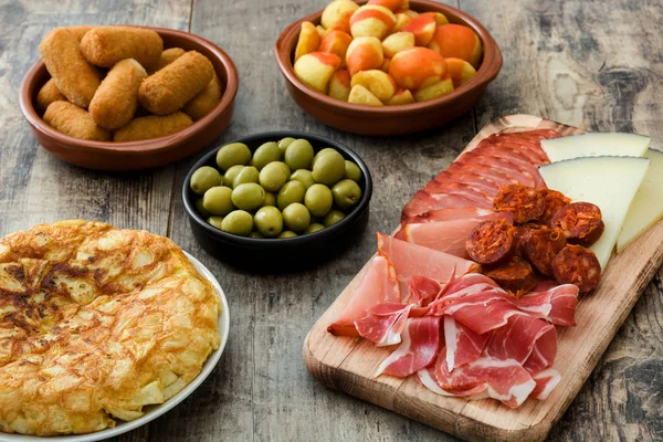 Traditional spanish tapas. Croquettes, olives, omelette, ham and patatas bravas on wooden table — Stock Photo, Image