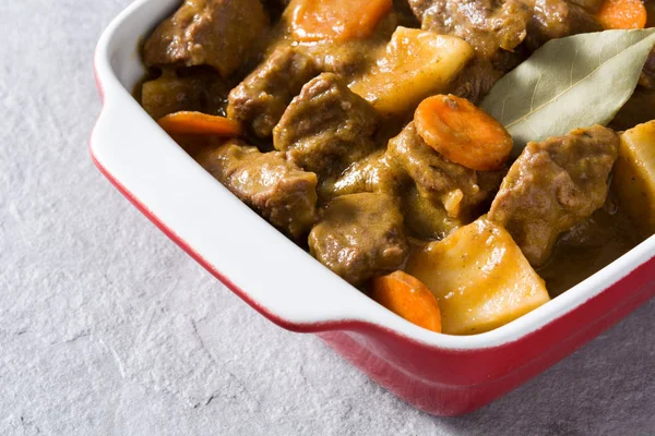 Rundvlees, gestoofd met aardappelen, wortelen en specerijen in keramische pot op grijze steen — Stockfoto