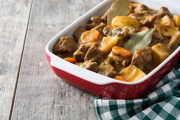 Beef meat stewed with potatoes, carrots and spices in ceramic pot on wooden table — Stock Photo, Image