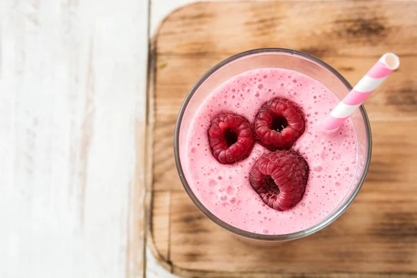 Raspberry smoothie in glass on white wooden table — Stock Photo, Image