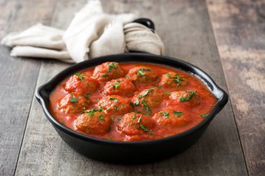 Ahşap masa üzerinde demir tavada domates soslu köfte