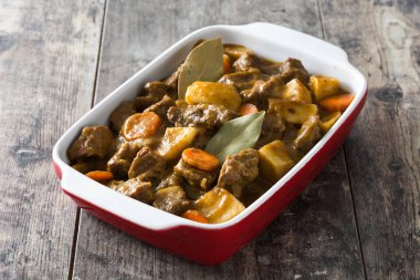 Patates, havuç ve ahşap masa üzerinde seramik tencerede baharatlar ile sığır eti Komposto