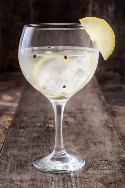 Vaso de gin tonic con limón sobre fondo de madera — Foto de Stock