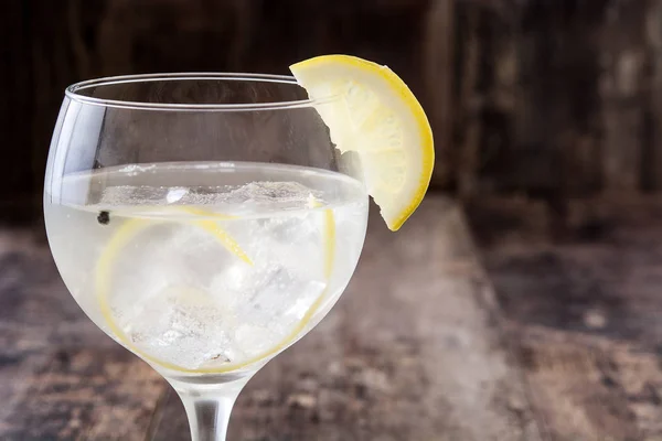 Glass of gin tonic with lemon on wooden background — Stock Photo, Image