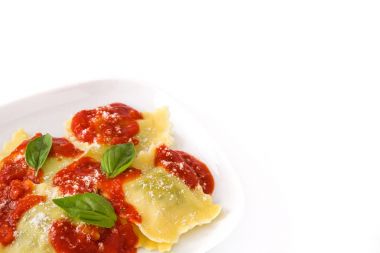 Beyaz arkaplanda domates soslu ve fesleğenli Ravioli.