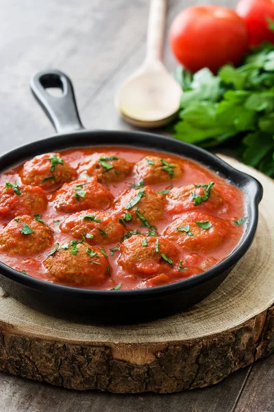 Albóndigas con salsa de tomate en sartén de hierro sobre mesa de madera — Foto de Stock