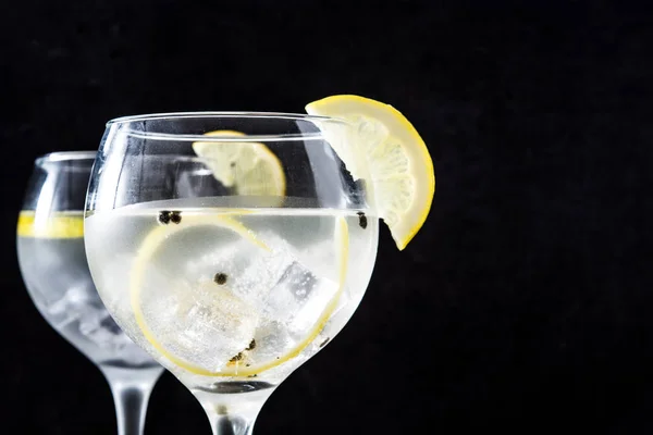 黒い石の背景にレモンのジントニックのグラス — ストック写真
