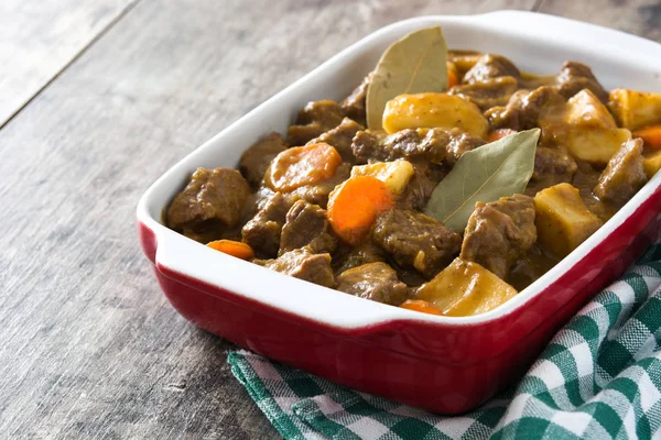 Beef meat stewed with potatoes, carrots and spices in ceramic pot on wooden table — Stock Photo, Image