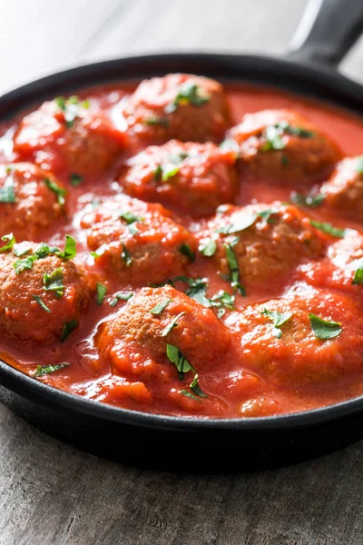 Albóndigas con salsa de tomate en sartén de hierro sobre mesa de madera . —  Fotos de Stock