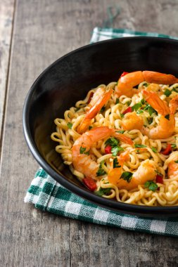 Erişte ve ahşap masa üzerinde siyah kase sebzeli karides