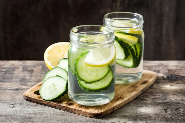 Detox water with cucumber and lemon on wooden table