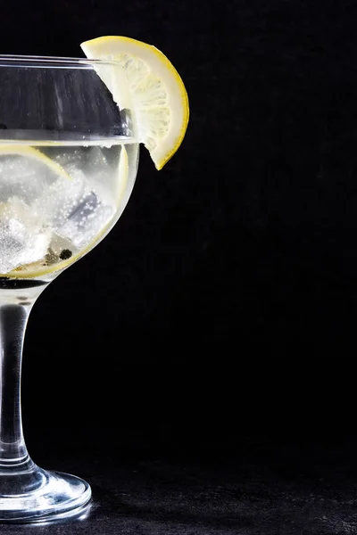 Glass of gin tonic with lemon on black stone background — Stock Photo, Image