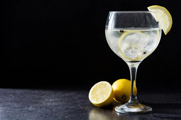 Glass of gin tonic with lemon on black stone background — Stock Photo, Image