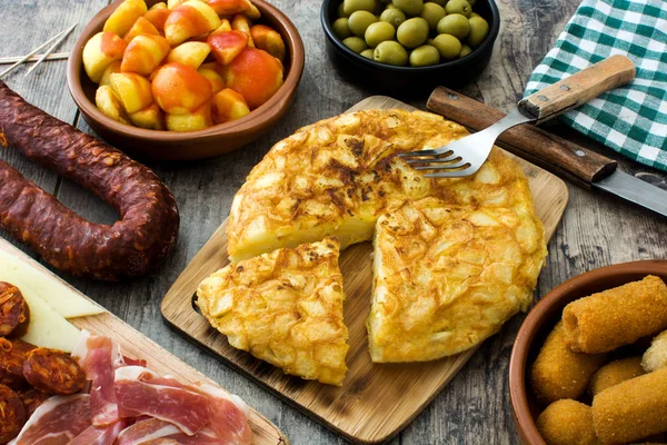 Tapas tradicionales españolas. Croquetas, aceitunas, tortilla, jamón y patatas bravas sobre madera — Foto de Stock