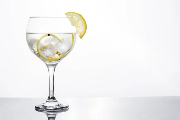 Vaso de gin tonic con limón sobre fondo blanco — Foto de Stock