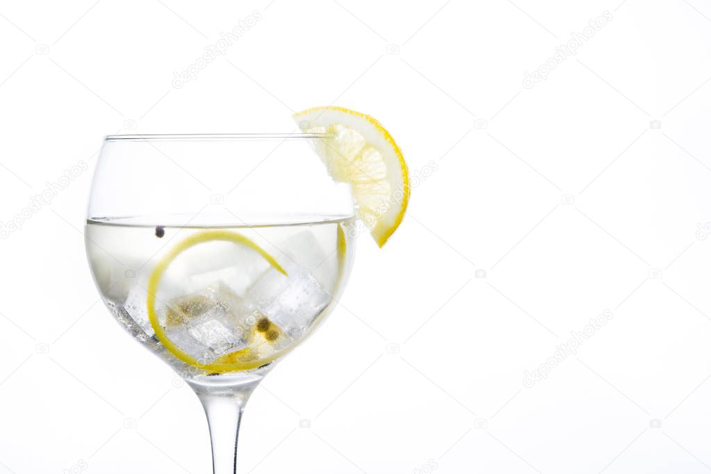 Glass of gin tonic with lemon on white background
