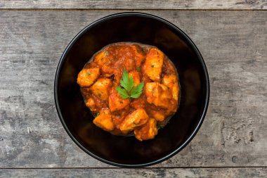 Ahşap masa üzerinde bir kapta tavuk tikka masala
