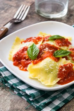 Domates sosu ve ahşap masa üzerinde fesleğen ile mantı