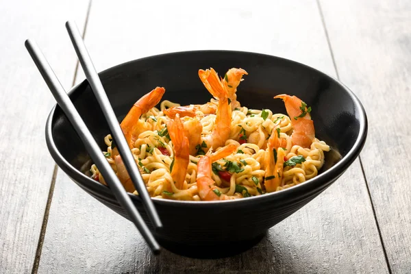 Erişte ve ahşap masa üzerinde siyah kase sebzeli karides