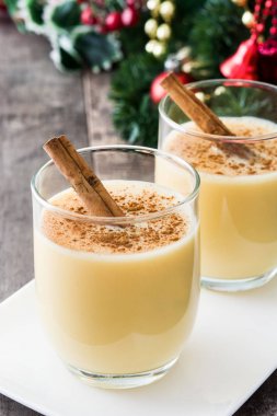 Tarçın ahşap masa üzerinde ev yapımı yumurta likörü. Tipik Noel tatlısı.